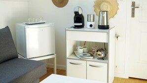 Un espacio habitable pequeño con un sofá, un armario blanco con electrodomésticos de cocina y una puerta con manija.