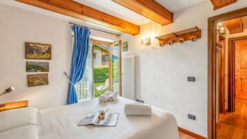 A bedroom with a bed, a window with curtains, a wall-mounted light fixture, and a radiator.