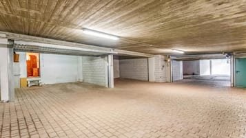 Een parkeergarage binnenshuis met bakstenen vloer, betonnen muren en een houten plafond.