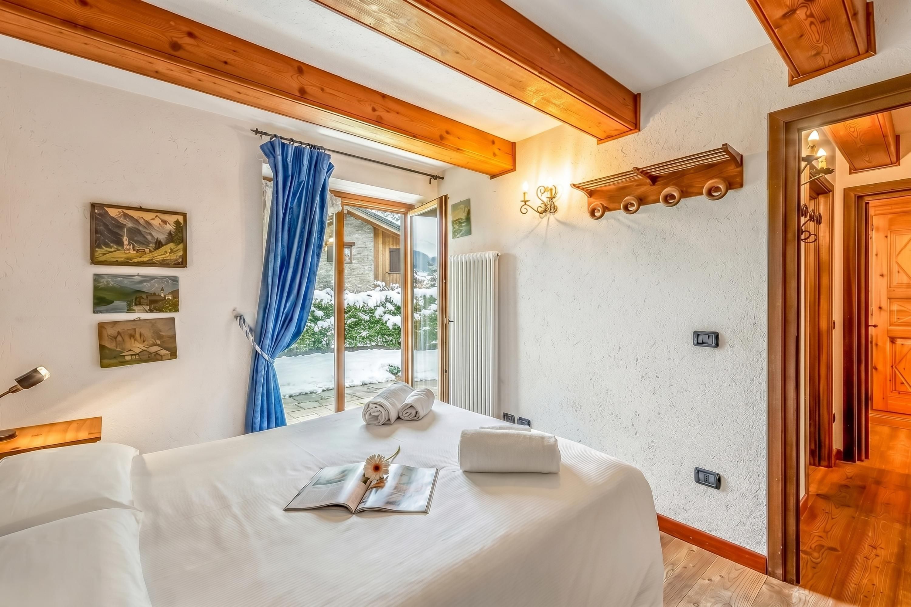 Un dormitorio con una cama grande, una ventana con cortinas e iluminación en la pared.
