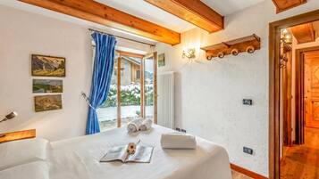 Un dormitorio con una cama grande, una ventana con cortinas e iluminación en la pared.