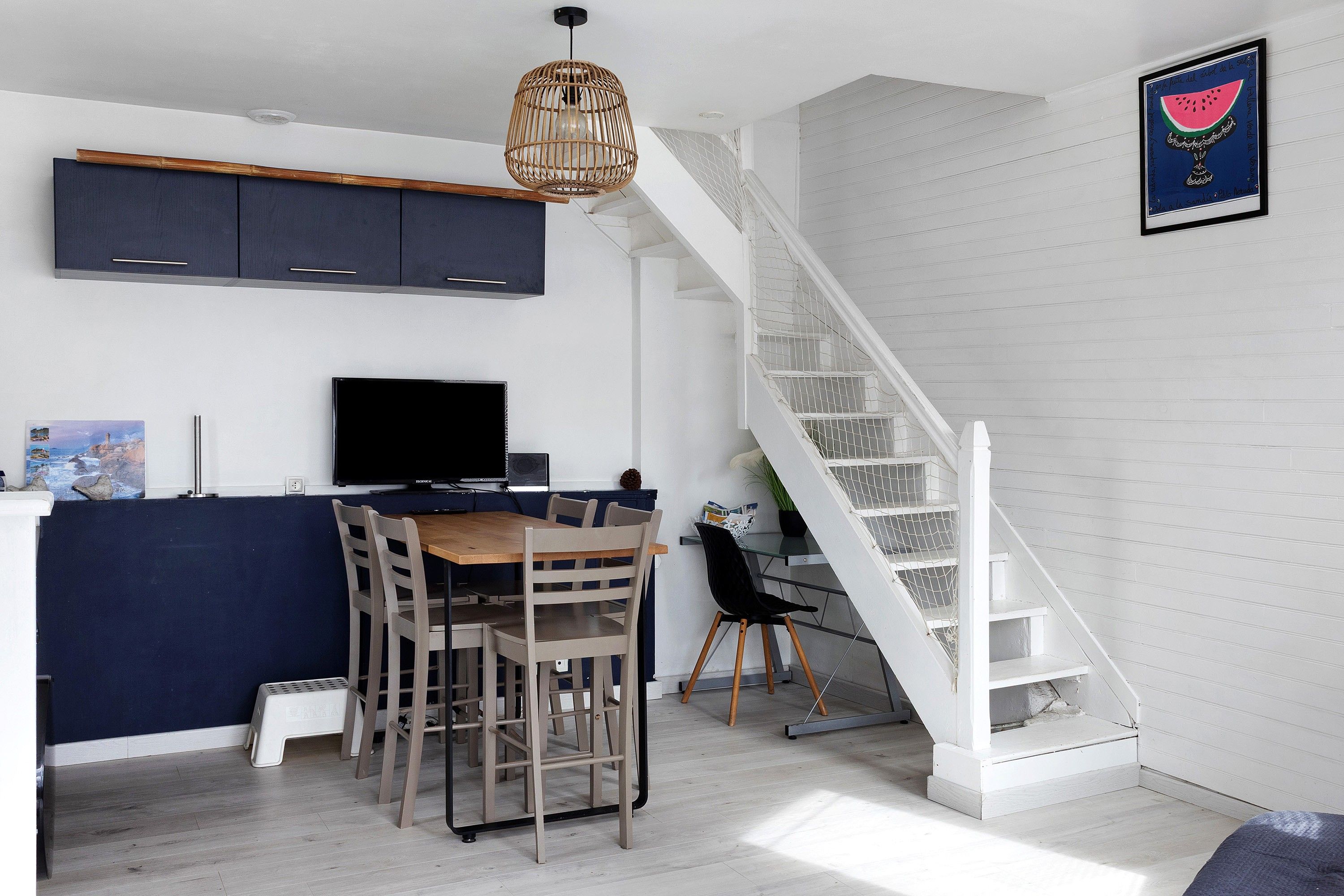 Une cuisine moderne avec des meubles de couleur sombre, une table à manger en bois et un escalier.