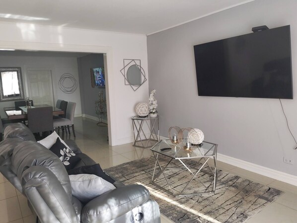 A modern living room with a leather sofa, a glass coffee table, and a flat-screen TV mounted on the wall. - Apartment in Heredia, Costa Rica (San Francisco)