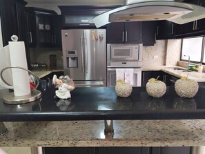 A modern kitchen with stainless steel appliances, a granite countertop, and decorative items.