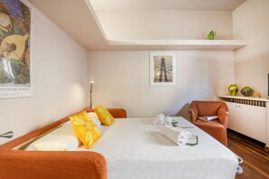 A hotel room with a bed, a chair, a desk, a lamp, and artwork on the walls. - PALERMO, 14 – Garibaldi/Brera Modern Suite (Milan)