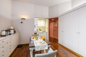 A compact kitchen with a dining table set for breakfast, a coffee maker, and a kettle on the counter. - PALERMO, 14 – Garibaldi/Brera Modern Suite (Milan)