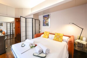 A hotel room with a bed, a desk, a chair, a bedside table, and a wall-mounted artwork. - PALERMO, 14 – Garibaldi/Brera Modern Suite (Milan)