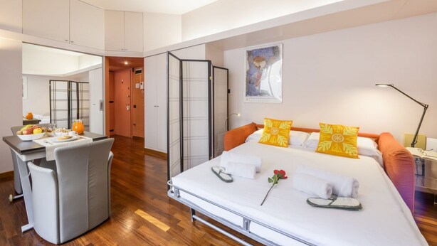 A modern hotel room with a bed, bedside table, and a small kitchenette area. - PALERMO, 14 – Garibaldi/Brera Modern Suite (Milan)