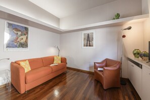 A modern living room with a wooden floor, a sofa, a chair, and artwork on the walls. - PALERMO, 14 – Garibaldi/Brera Modern Suite (Milan)