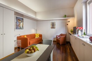 A modern kitchen with a dining table, a fruit bowl, a sofa, and a chair. - PALERMO, 14 – Garibaldi/Brera Modern Suite (Milan)
