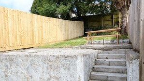 Een betonnen trap die leidt naar een houten terras met een bank.
