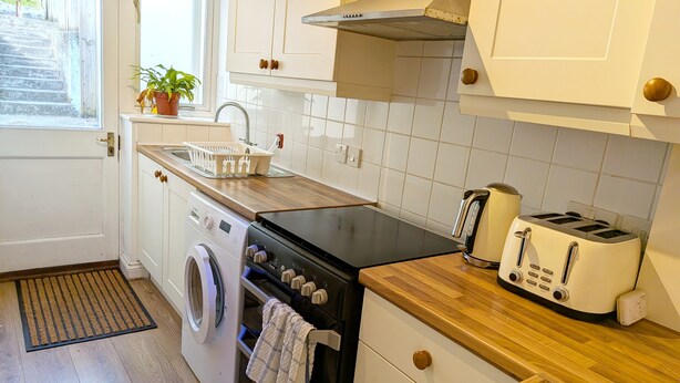 Een kleine keuken met een wasmachine, een broodrooster en een spoelbak.