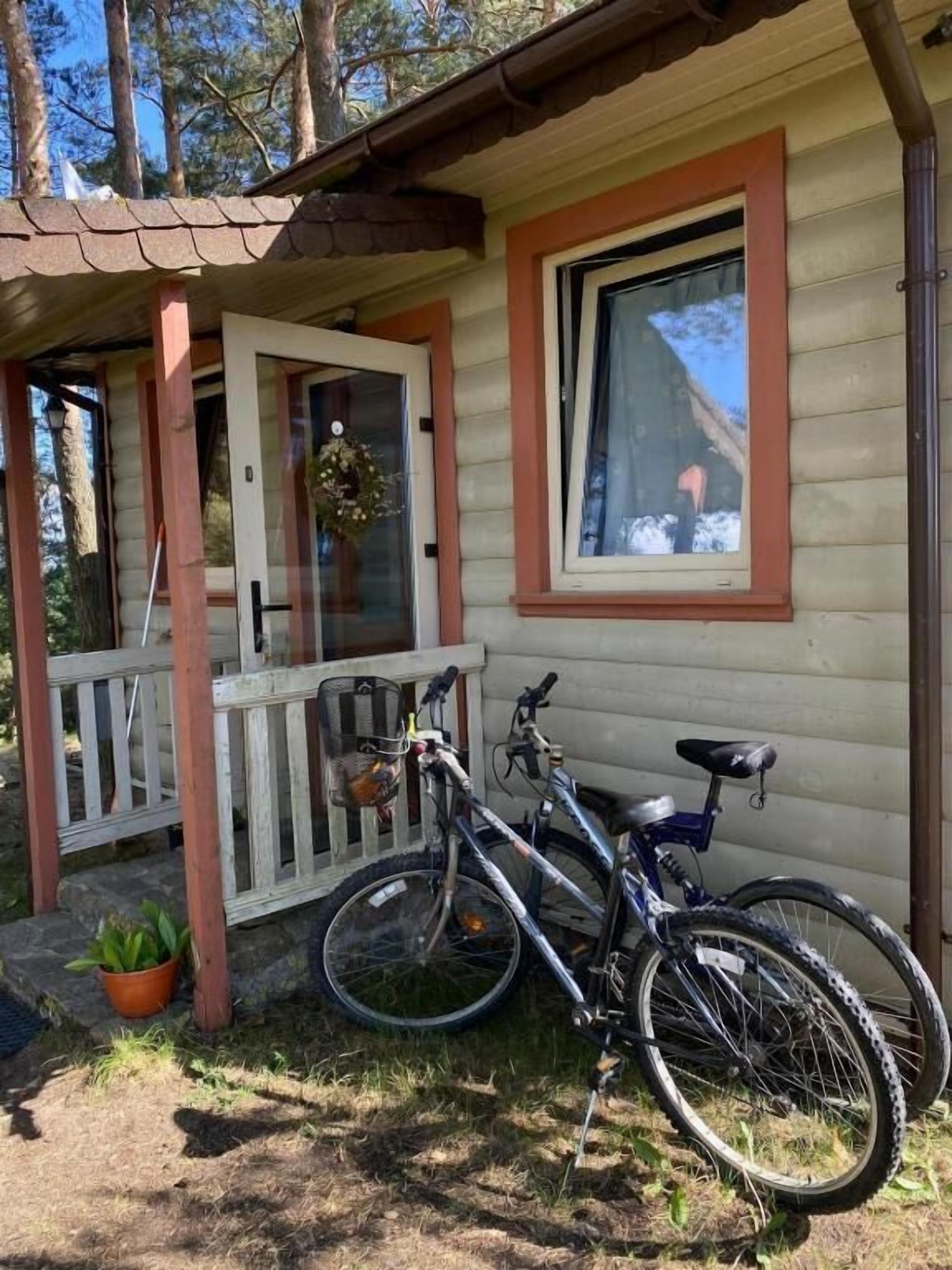 Una casa de madera con un porche, una bicicleta y una planta en maceta.
