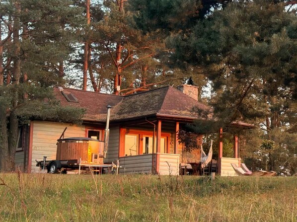 A rustic cabin with a chimney, a porch, and a hammock. - Cosy Cabin with Fireplace in Podlasie (Czarna Wieś Kościelna)