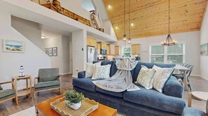 Ein geräumiger Wohnbereich mit einem blauen Sofa, Holzboden und einer Küche im Hintergrund.