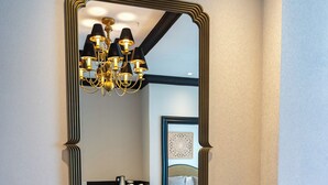 A room with a round table, two chairs, a large mirror, and a chandelier. - Baku Resort & Spa (Cholpon-Ata)