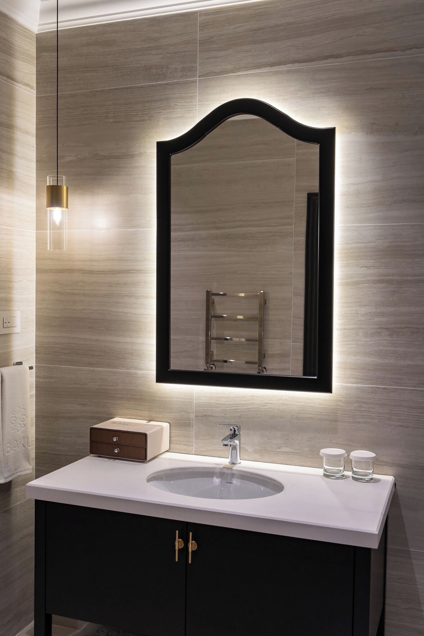 Un bagno moderno con un grande specchio, un lavandino bianco e un portasciugamani.