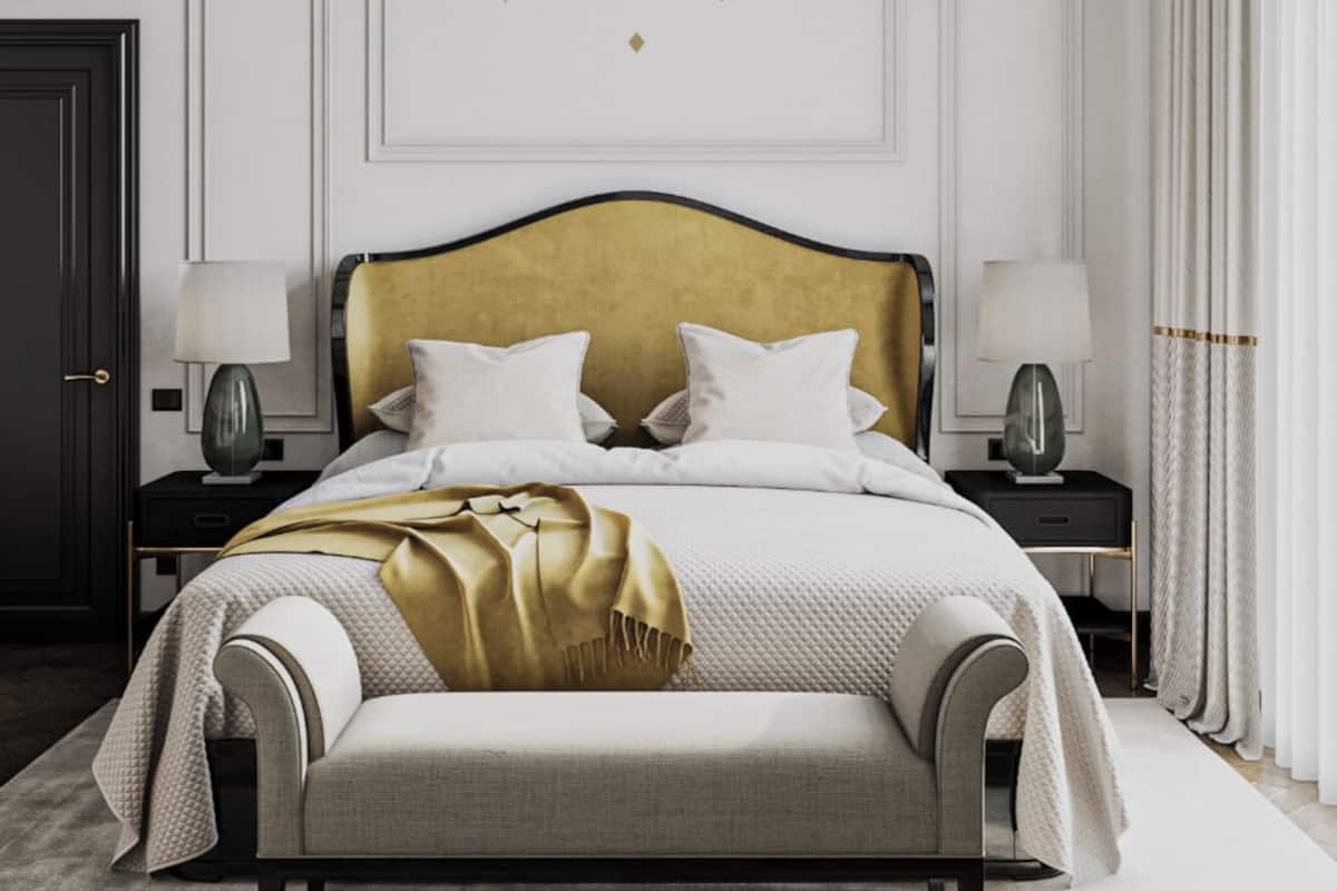 Quarto com uma cama, duas mesas de cabeceira, um candelabro e um detalhe decorativo na parede.