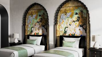 A hotel room with two beds, a large mural on the wall, a black ceiling light, and a small table with a lamp.
