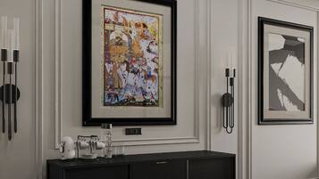 A hallway with framed artwork on the walls, a dark wooden console table with a coffee machine, and a black telephone.