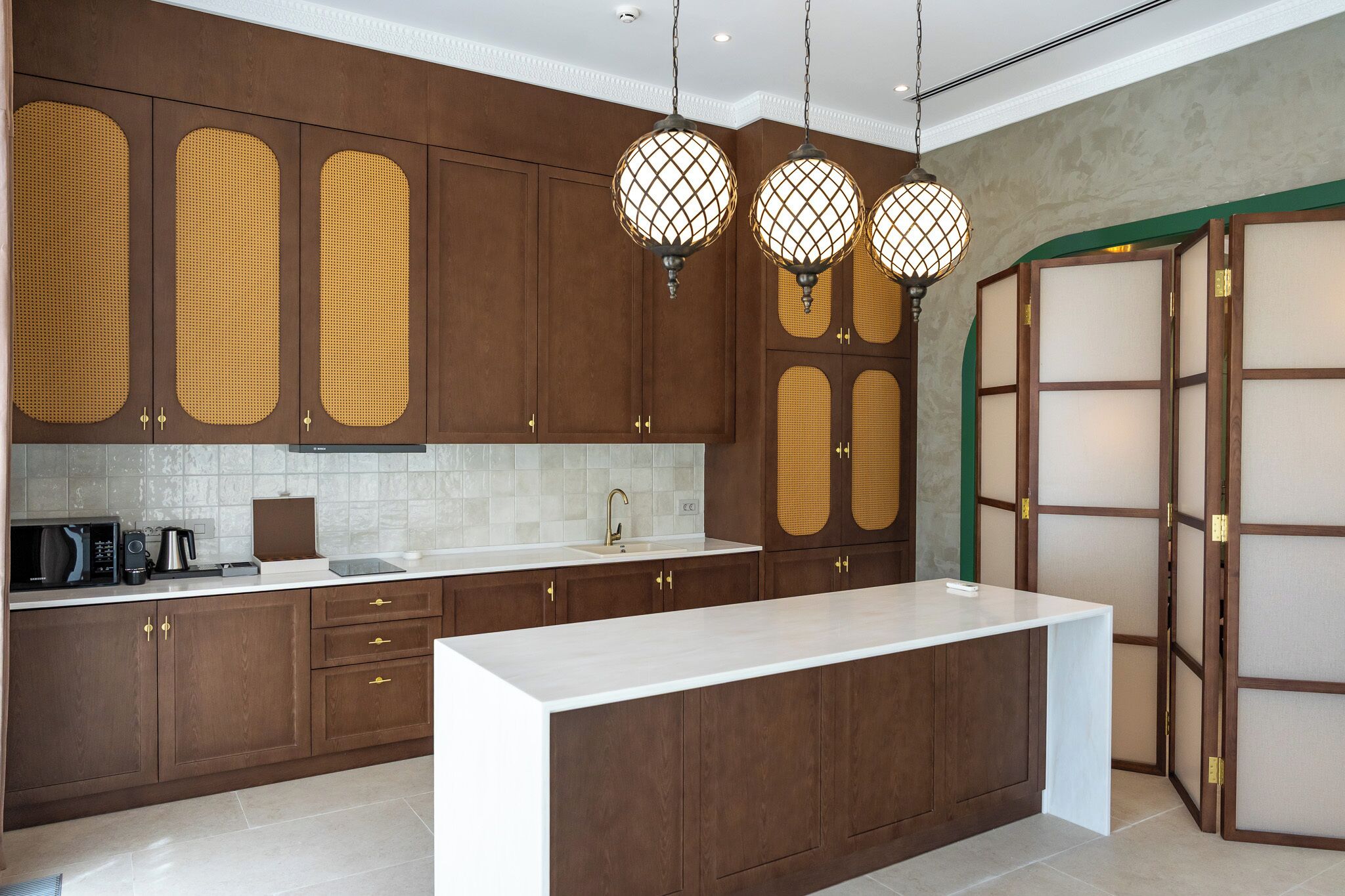 A modern kitchen with wooden cabinets, a white countertop, and pendant lights.