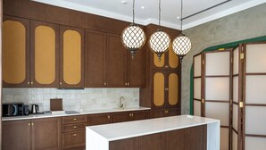 Una cocina moderna con armarios de madera, encimera blanca e iluminación colgante.