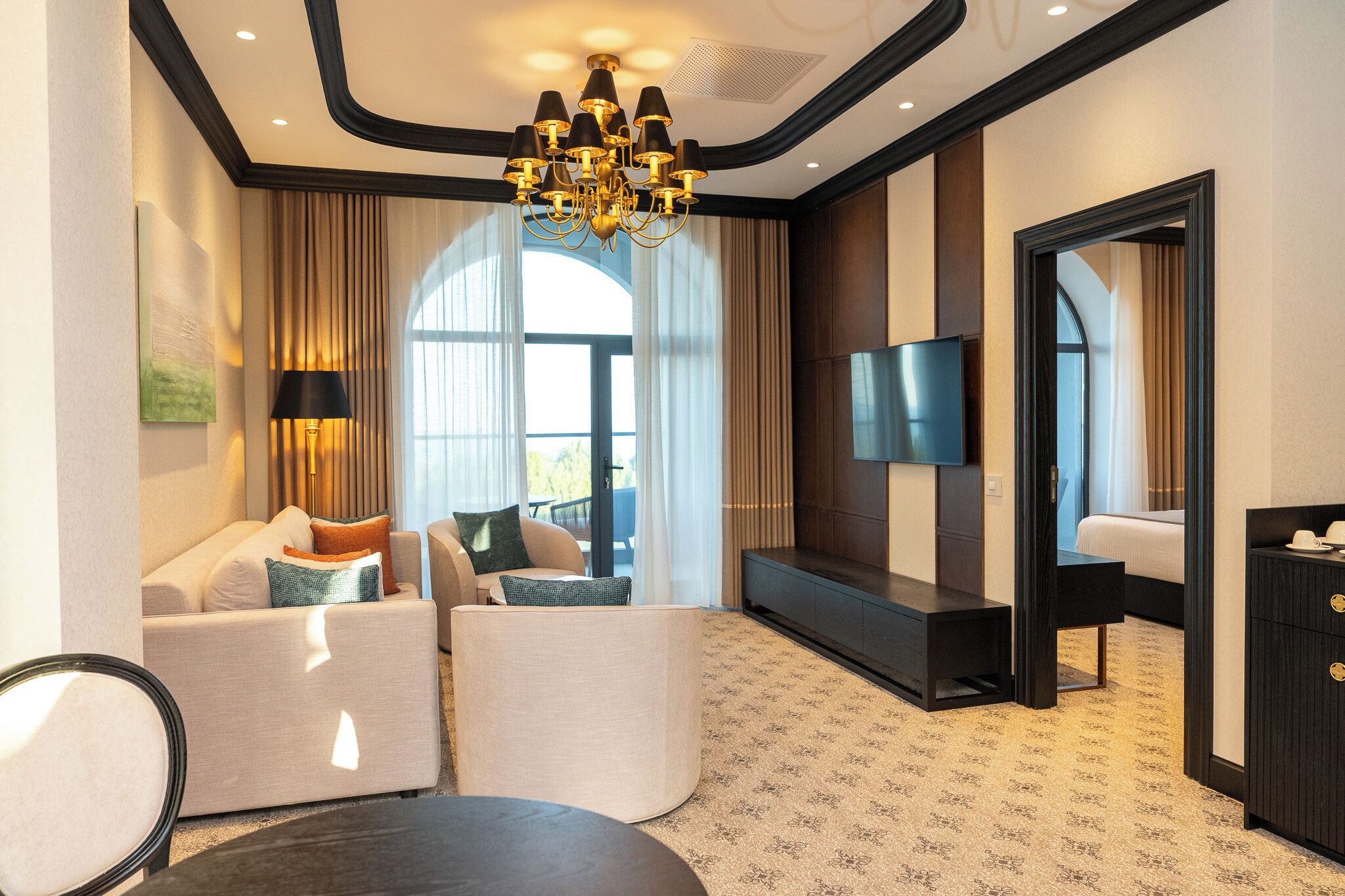 Habitación de hotel con sofá, televisor de pantalla plana, escritorio y candelabro.