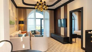Habitación de hotel con sofá, televisor de pantalla plana, escritorio y candelabro.