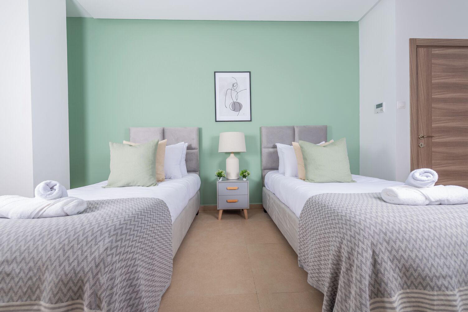 Habitación doble con dos camas, una mesita de noche, una lámpara y un cuadro en la pared.