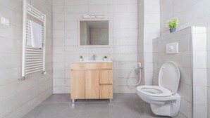A modern bathroom with a wooden vanity, a mirror, a toilet, and a shower. - Appartement Charmant a hydra (Algiers)
