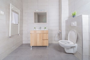 Un baño moderno con tocador de madera, un espejo, un inodoro y una ducha.