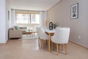 Een moderne woonkamer met een bank, eettafel, stoelen en een lamp.