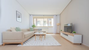 A modern living room with a sofa, coffee table, TV, and a plant. - Appartement Charmant a hydra (Algiers)