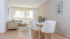 A modern living room with a sofa, dining table, and chairs, a window with curtains, and a framed artwork on the wall. - Appartement Charmant a hydra (Algiers)