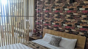 Uma cama com cabeceira de madeira, almofada estampada em padrão de zebra e colcha xadrez.