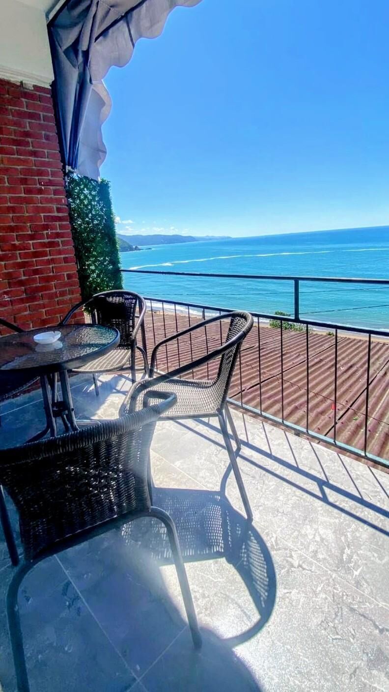 A balcony with a view of the sea, featuring a table and two chairs.