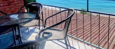 A balcony with a view of the sea, featuring a table and two chairs.