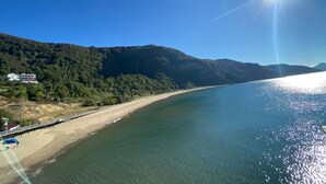 Un paisaje costero con una playa, un muelle y un edificio en una ladera.
