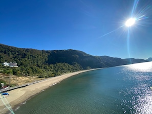 Un paisaje costero con una playa, un muelle y un edificio en una ladera.