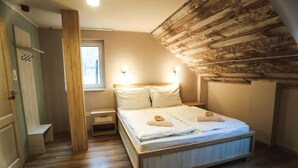 Un dormitorio con techo de madera, cama con ropa blanca, mesita de noche y ventana.