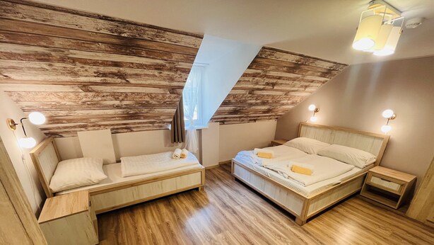 Un dormitorio con cama altillo, una cama tipo diván y una mesita de noche pequeña.