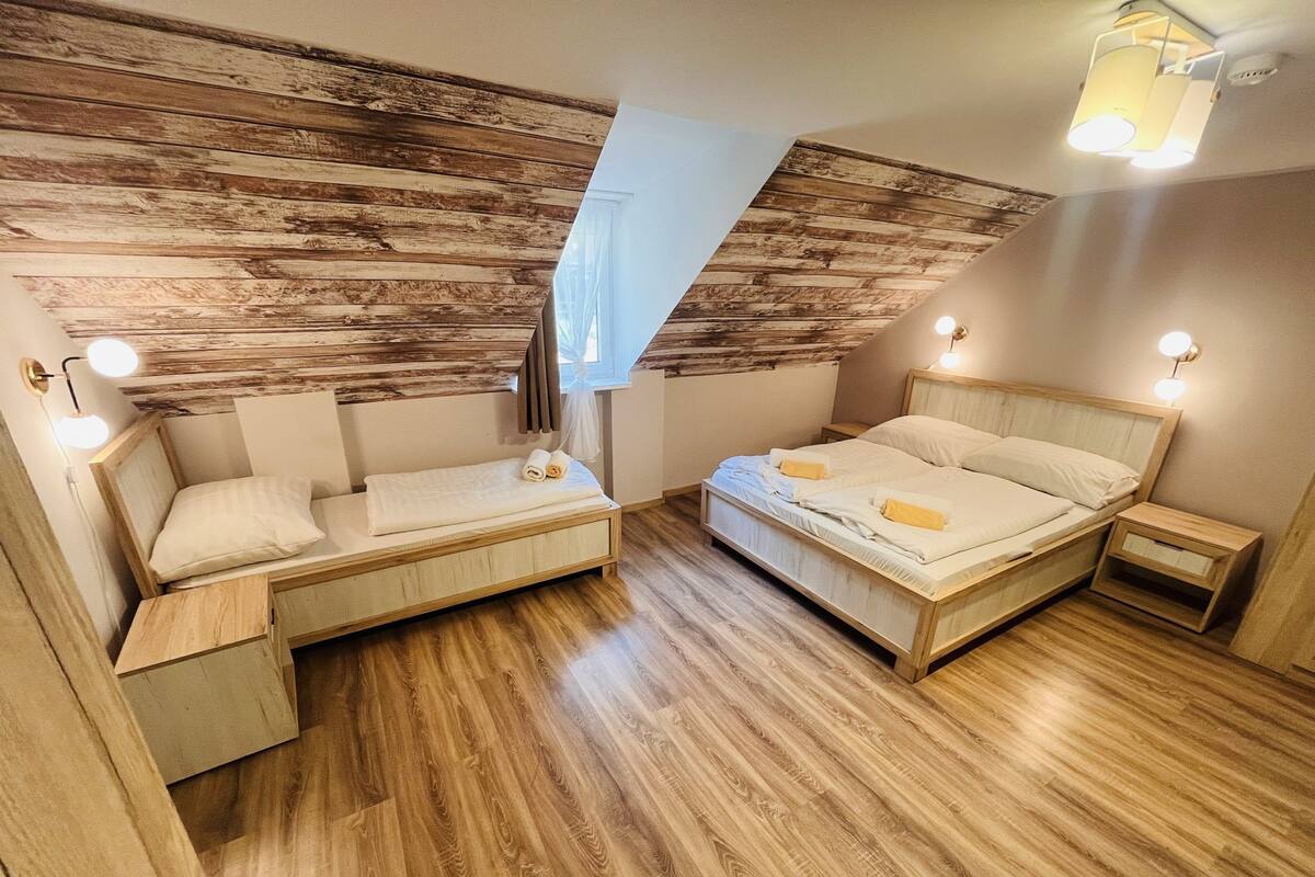 A bedroom with a loft bed, a daybed, and a small bedside table.