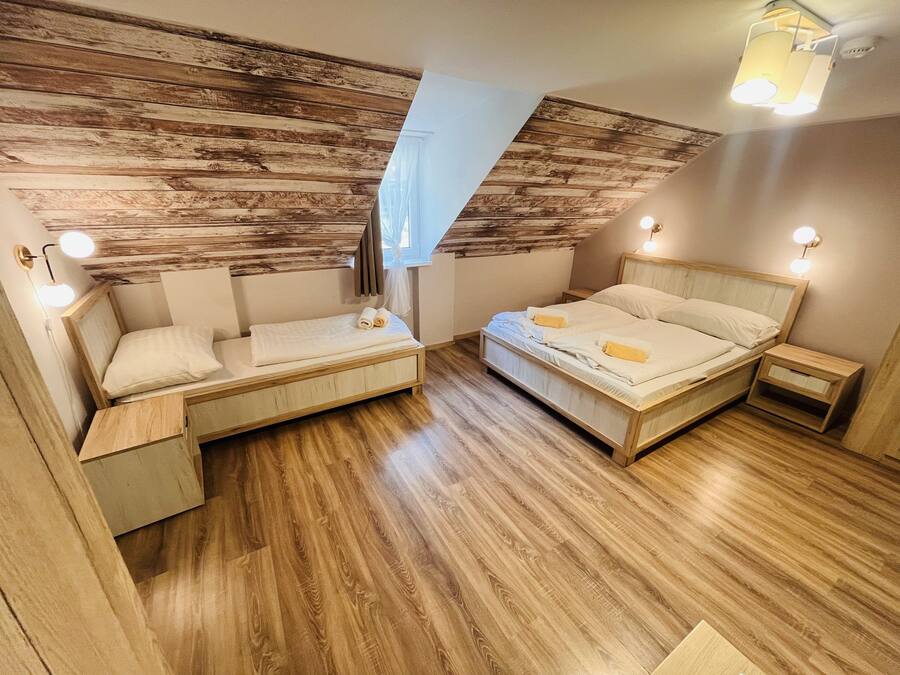 Un dormitorio con cama altillo, una cama tipo diván y una mesita de noche pequeña.