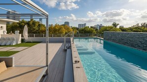 A rooftop pool with a wooden deck, lounge chairs, and a view of the city skyline. - 4BR Brickell Luxury, Rooftop Pool, PingPong, City Views (Miami)