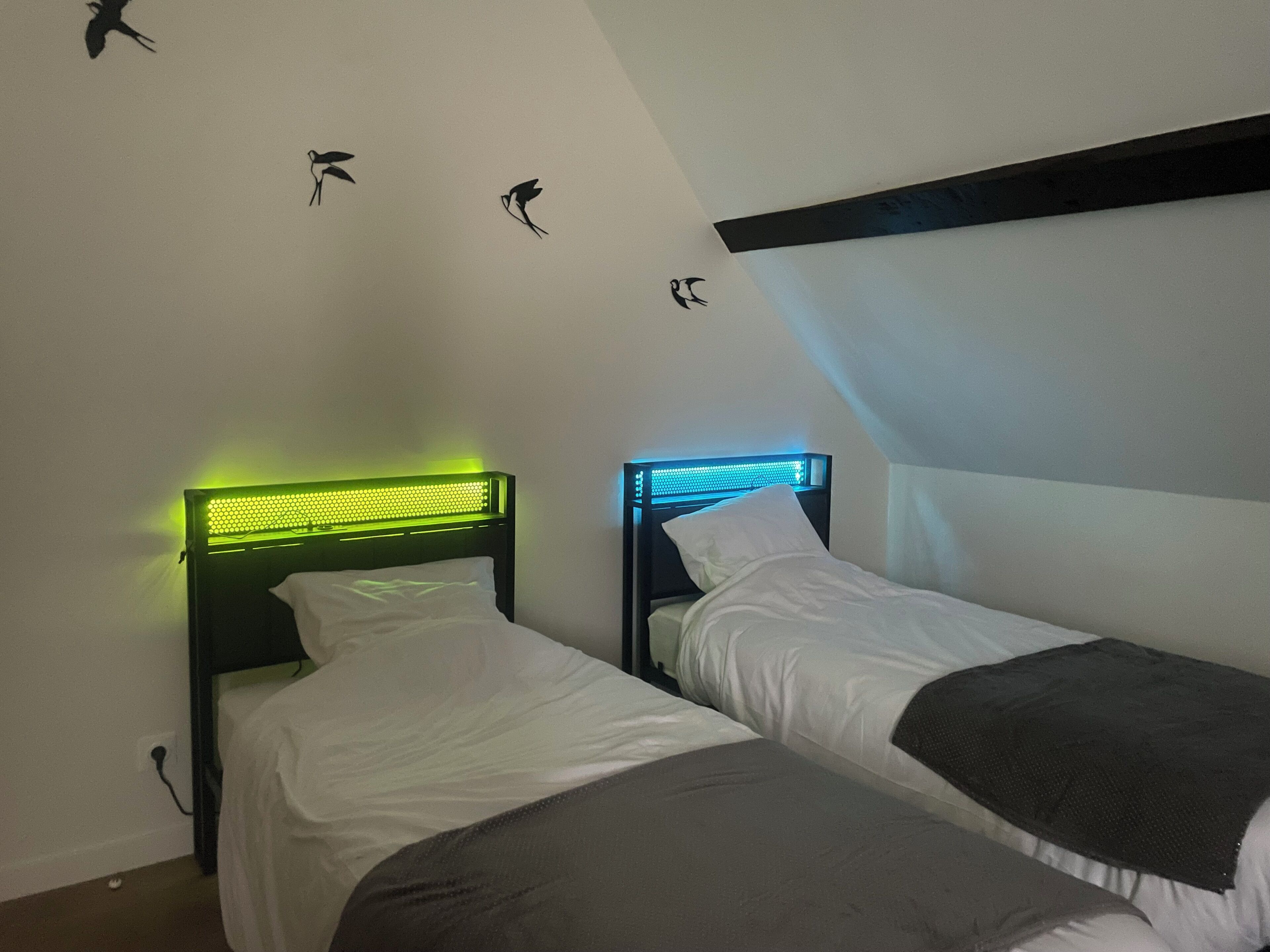 A room with two beds, each with a headboard featuring LED lighting.