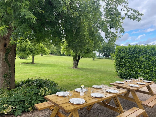 Une table de pique-nique installée à l’extérieur, avec des assiettes, des couverts et des verres.