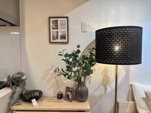 Ein Zimmer mit Nachttisch aus Holz, einer schwarzen Lampe, einem gerahmten Foto und einer kleinen Pflanze.
