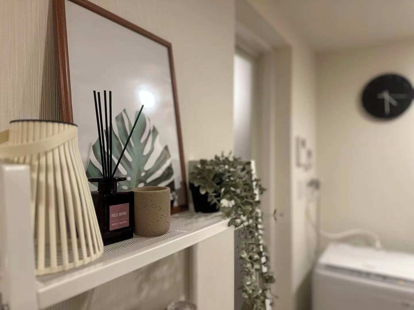 A shelf with a lamp, a framed picture, a potted plant, and a small container.