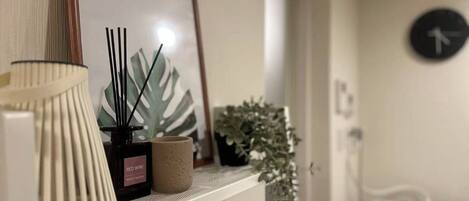 A shelf with a lamp, a framed picture, a potted plant, and a small container.
