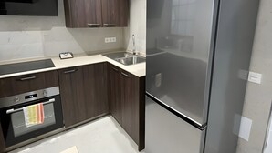Una cucina moderna con frigorifero in acciaio inossidabile, pensili in legno scuro, forno integrato e un piano di lavoro elegante.